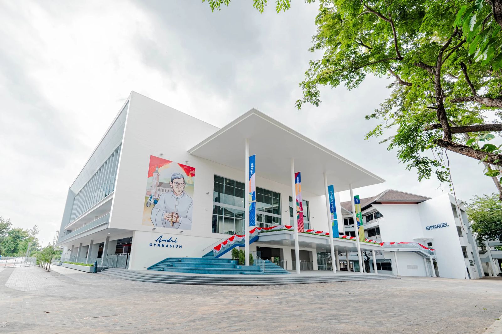 อาคาร André Gymnasium ของโรงเรียนมงฟอร์ตวิทยาลัย ผนังสีขาว หลังคายื่นเหนือบันไดทางเข้า